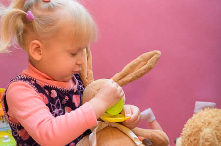 The little girl is playing with any soft toys