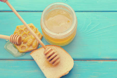 Honey and honey accessories for its use on a blue wooden background.の写真素材