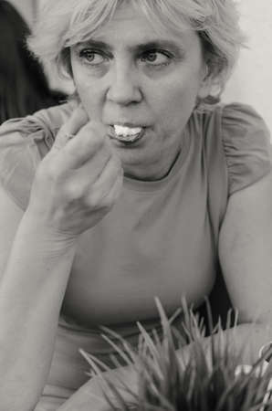 A woman of 45-50 years old sits sadly in a cafe with a cup of tea.の写真素材