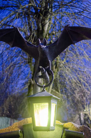 The statue of a bat with a flashlight in its paws at night.のeditorial素材
