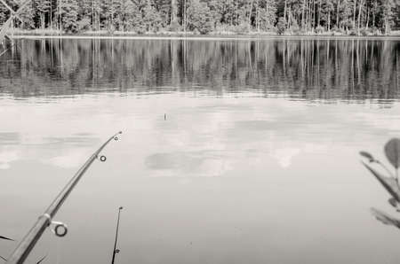 Fishing rod, water surface, float, day, reflection of clouds.の写真素材