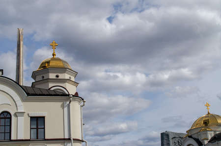 The obelisk of the Brest fortress against the background of the Orthodox church and the cloudy sky.