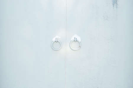 A closed gray gate with round handles sprinkled with snow.の写真素材