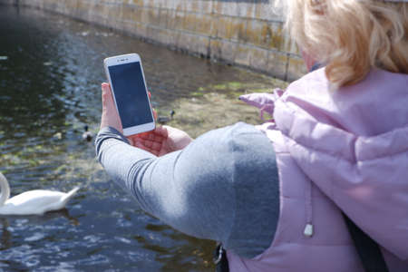A girl in a white cap photographs the water landscape on the phone. St. Veronicas Day Photographers Day .の写真素材