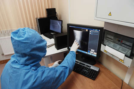 The work of a radiologist in antiviral overalls in the X-ray room for diagnostics.