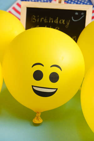 Yellow emoji balloons on the background of the board with the event inscription and American flags.の写真素材
