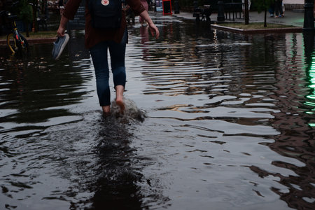 City streets after heavy rain. Barefoot on sidewalks with puddles and reflections.の写真素材