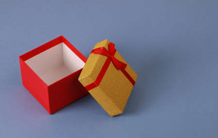 Red gift box. Yellow lid. Closeup of gift box on blue background.Birthday, valentine, anniversary or...
