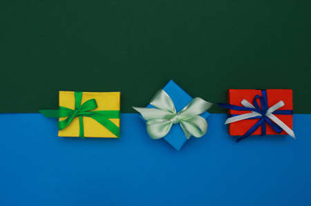 Yellow, blue, red gift boxes with bows on two color paper background of blue and green. ..Image of gifts, top view. Holiday concept. Birthday greetings. Valentines Day greeting.の写真素材