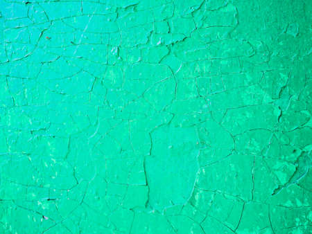 Wall with old damaged light green paint. Damaged weathered green background, old with paint worn metal wall surface texture.の写真素材