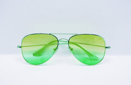 Sunglasses with a green gradient on a white wall background close-up.の写真素材