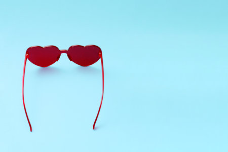 Beautiful sunglasses in the shape of a heart on a blue background.の写真素材