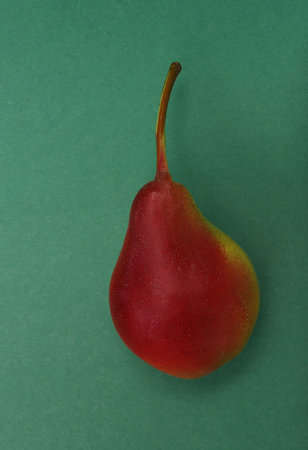 Juicy and ripe red pear on a green paper background. fruit concept.の写真素材