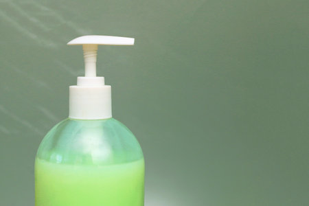 A green plastic bottle with liquid soap on an uneven background. Hygiene products.の写真素材