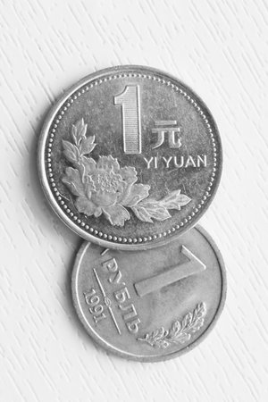 Vertical photo of one Russian ruble and one Chinese yuan on a white background.の写真素材