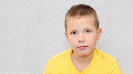 Portrait of a little boy in a yellow t-shirt on a white backgroundの写真素材