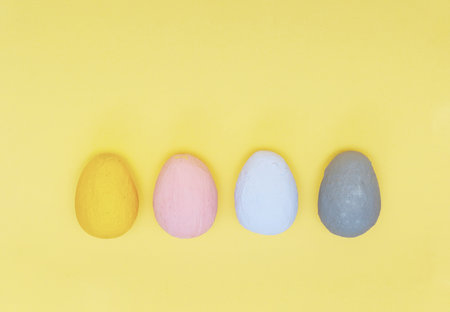 Yellow, pink, white, gray eggs on a yellow pastel paper background. concept of a holiday and a happy...