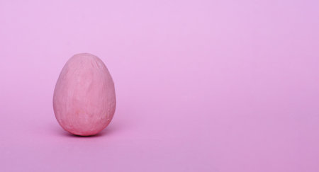 Dark pink decorative egg on a red background. Happy Easter background. Minimal Easter.の写真素材