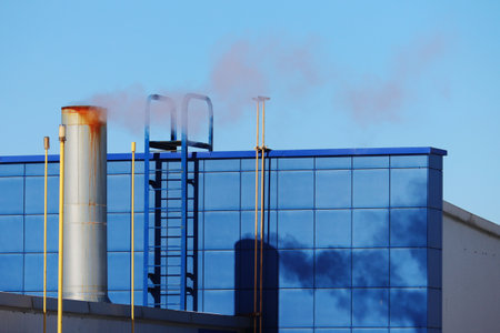 Chimneys of a heating system on the facade of a residential building, Europe. Chimney with smoke, stairs, wall, building facade in blue.の写真素材