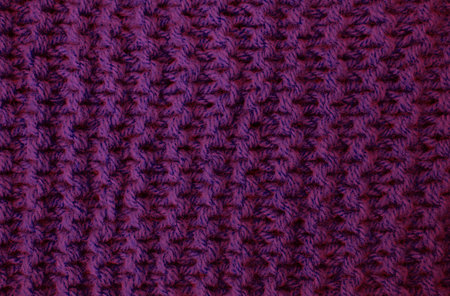 Abstract background of purple knitted woolen threads close-up.