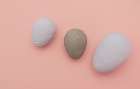 Two blue and one brown homemade decorative eggs on a pink paper background.の写真素材