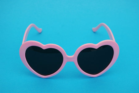 Pink heart-shaped sunglasses on a blue background...Fashionable glamorous women's glasses.の写真素材