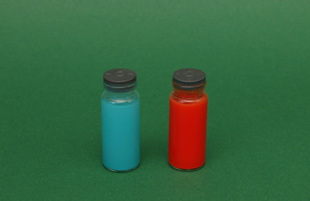 Two ampoules with red and blue chemical liquid on a blue paper background. Ampoules with a chemical...
