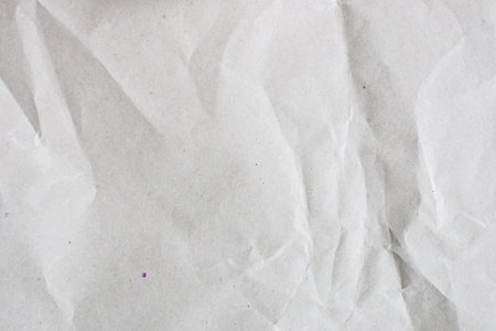 Cardboard background made of natural crumpled paper in light gray color.の写真素材