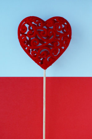 Decorative red gift heart on a stick on a two-colored background of red and blue. Valentine's Day...