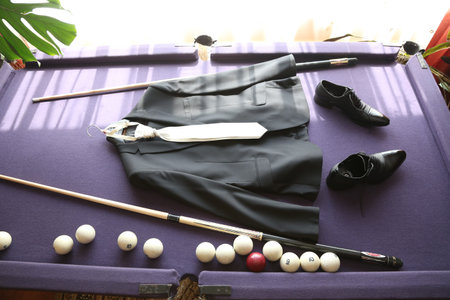 ..Black jacket, white tie, shoes, two billiard cues, billiard balls lie on the table.