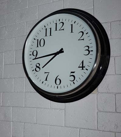 Black clock on the grey brick wallの写真素材