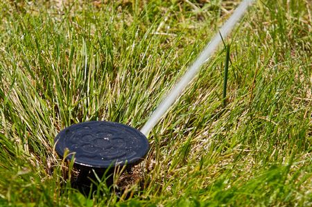 a field in summer is a sprinkler watering