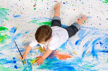 Handsome boy playing with painting with the background paintedの写真素材