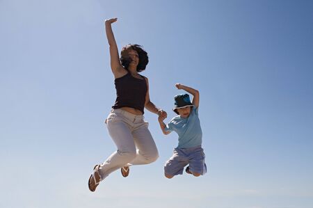 Mother and son jumping a over sky backgroundの写真素材