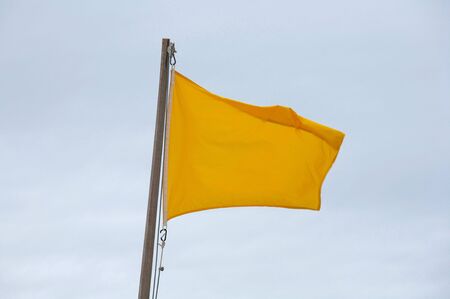 Yellow flag on the beach waving in the windの写真素材