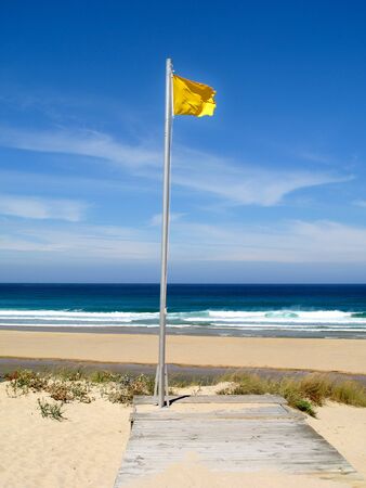 Beautiful landscape with waves breaking on the sea and yellow flagの写真素材