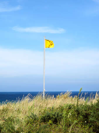 Beautiful landscape with waves breaking on the sea and yellow flagの写真素材