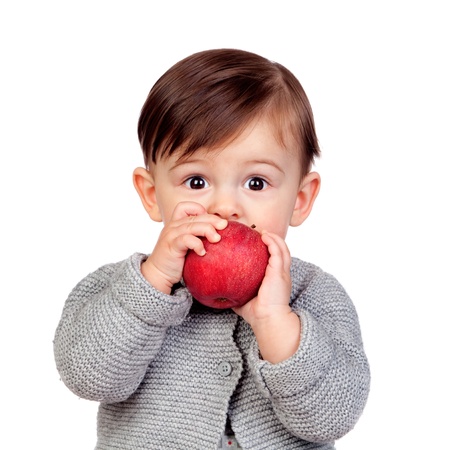 Adorable baby girl eating a red apple isolated on white backgroundの写真素材