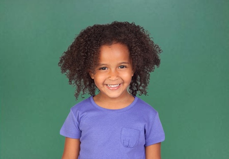 Adorable african little girl with beautiful hairstyle and a blackboard of backgroundの写真素材