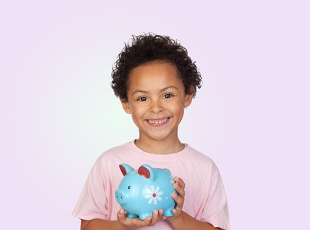 Happy latin child with a blue moneybox isolated on a purple backgroundの写真素材