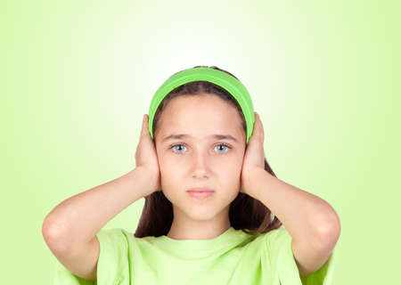 Frightened girl covering her ears isolated on a green backgroundの写真素材