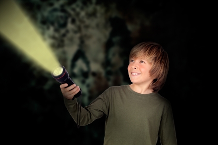 Child with a flashlight looking for something on darkness backgroundの写真素材