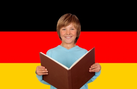 Preteen boy with a big book and the colors of German flag of backgroundの写真素材