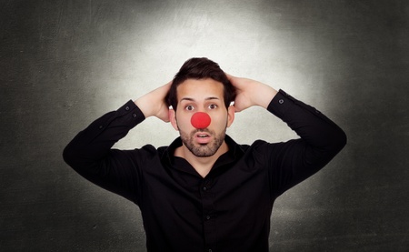Astonished businessman with clown nose on a over gray and irregular backgroundの写真素材