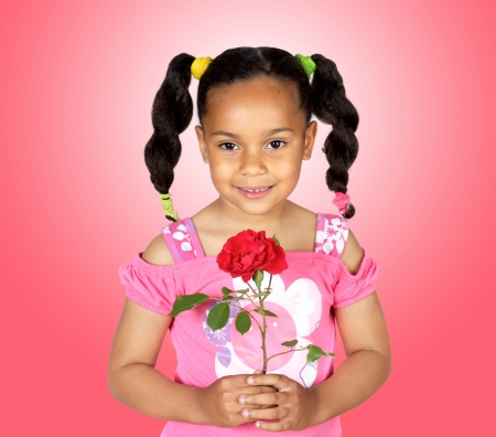 Smiling little girl with a red rose for gift on a over pink backgroundの写真素材