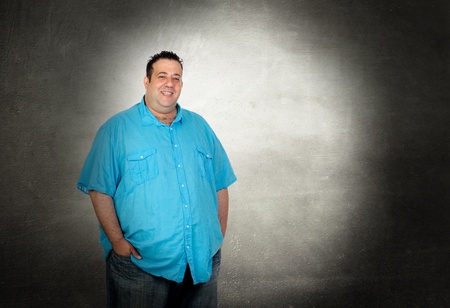 Happy fat man with blue shirt on a over gray backgroundの写真素材