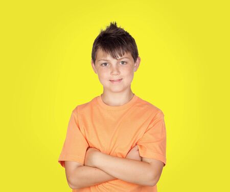 Smiling boy with arms crossed on yellow background