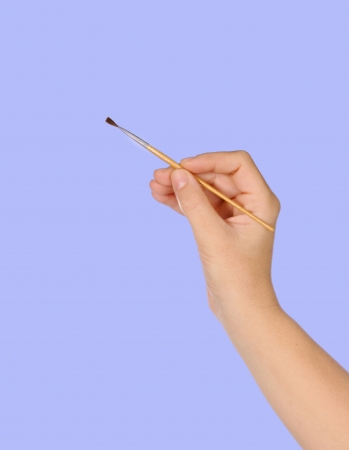 Hand painting with a brush on a blue backgroundの写真素材