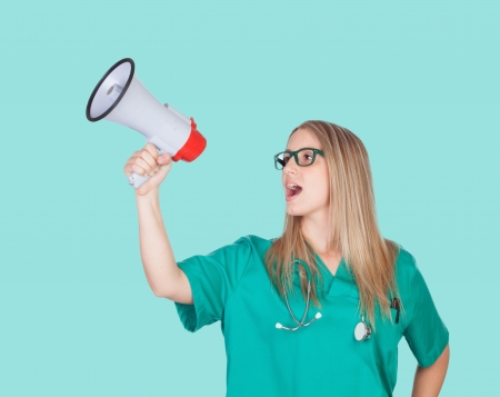 Atractive medical girl with a megaphone on a blue backgroundの写真素材