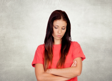 Depressed brunette girl dressed in red on a gray backgroundの写真素材